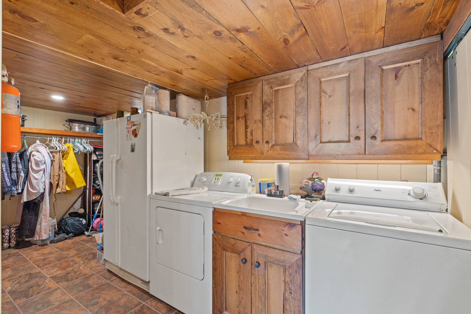 A small laundry area with a washer, a dryer, a sink, and a fridge.