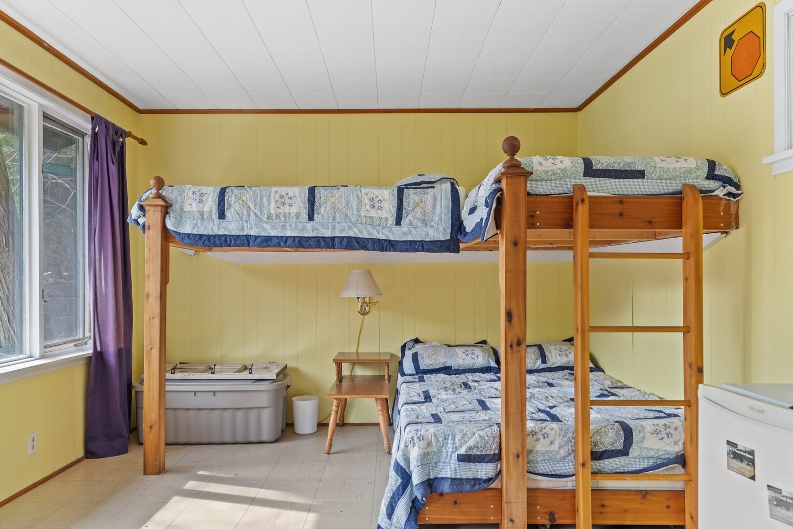 A bunkie sleeping space with bunkbeds for three people and yellow walls.
