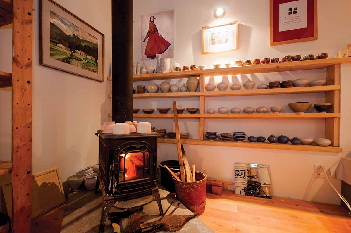 Babette's pottery studio with pieces lining the shelves on the wall