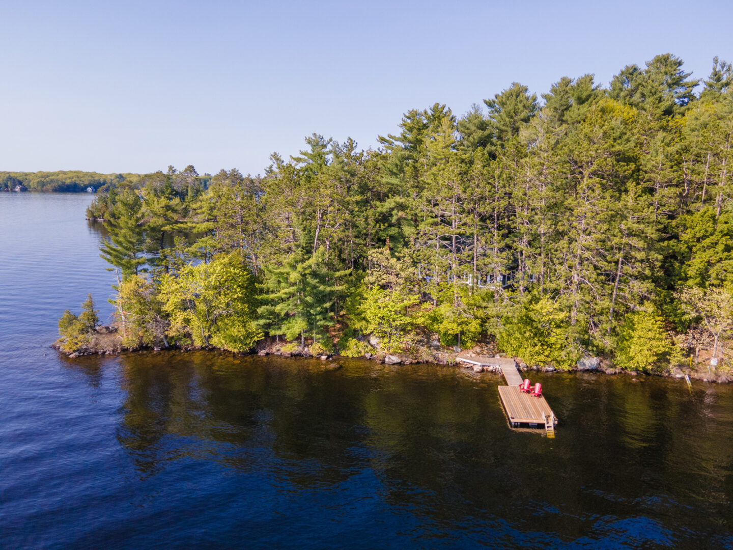 A long dock stretches into a blue lake along the shore of an island peninsula.