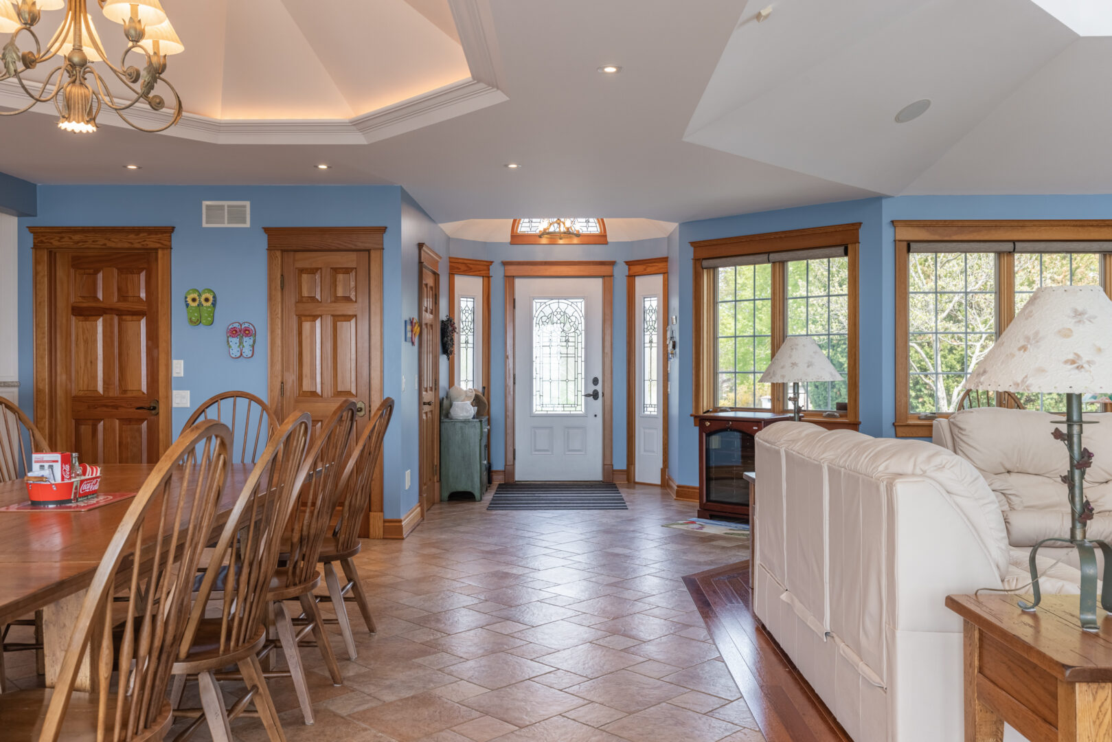 A bright entrance of a large lake house, with lots of windows, light blue walls, and hardwood floors.