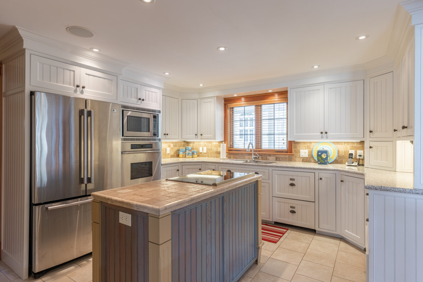 A big, bright kitchen with white cabinets and stainless steel appliances.