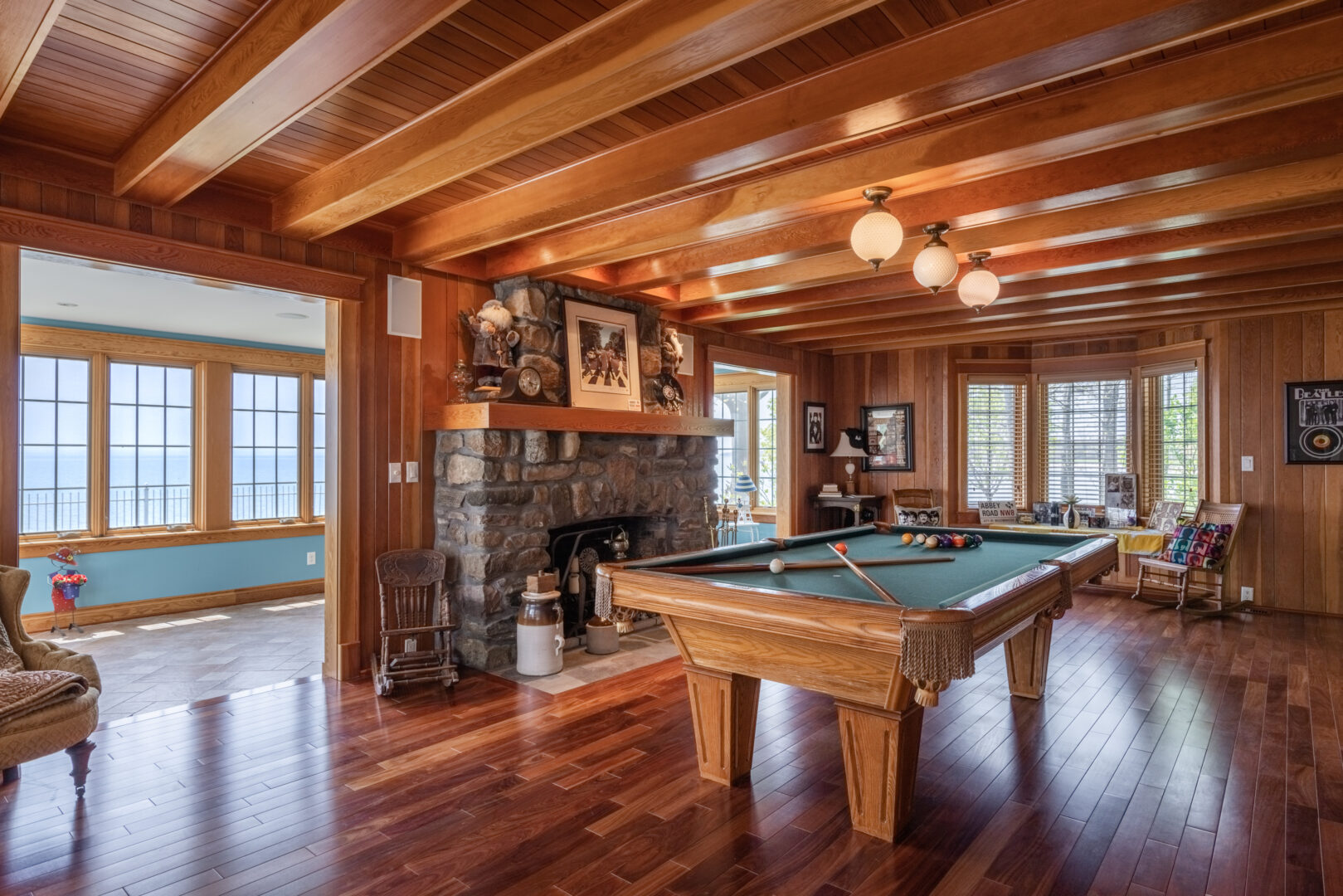 A large room with a pool table, leading into a bright sunroom.