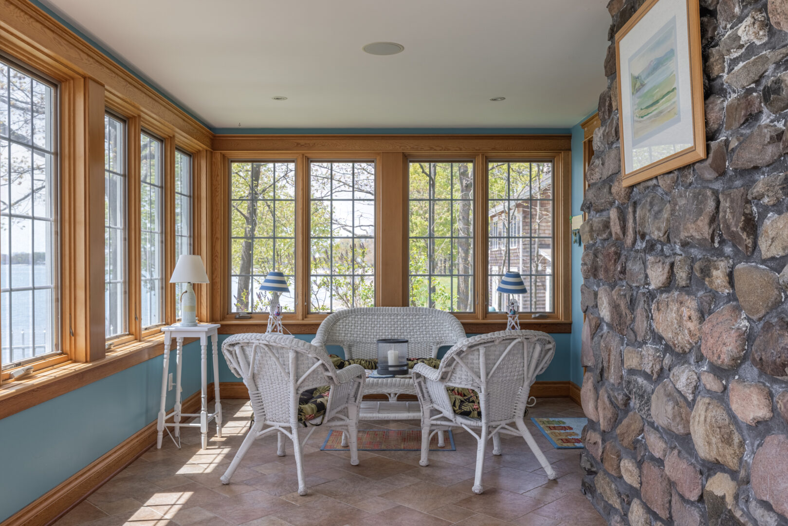 A bright sunroom with a small seating area that has white wicker furniture.