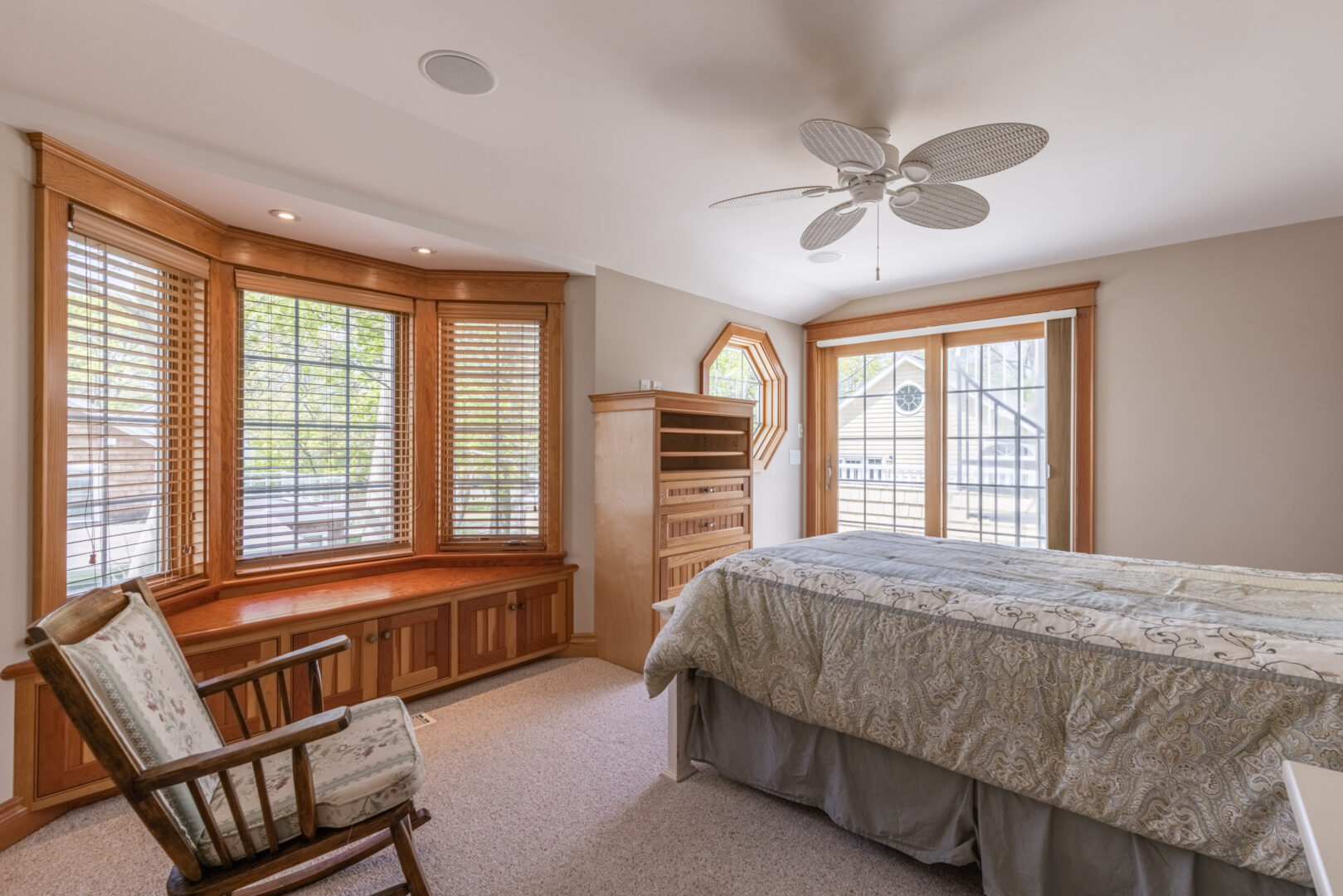 A big bedroom with lots of windows and a small bed.