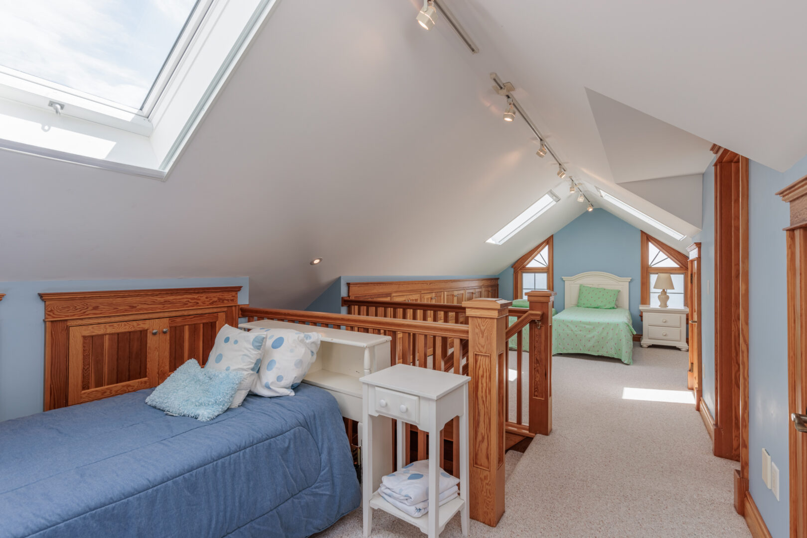 An attic bedroom space with two small beds and bright natural light.