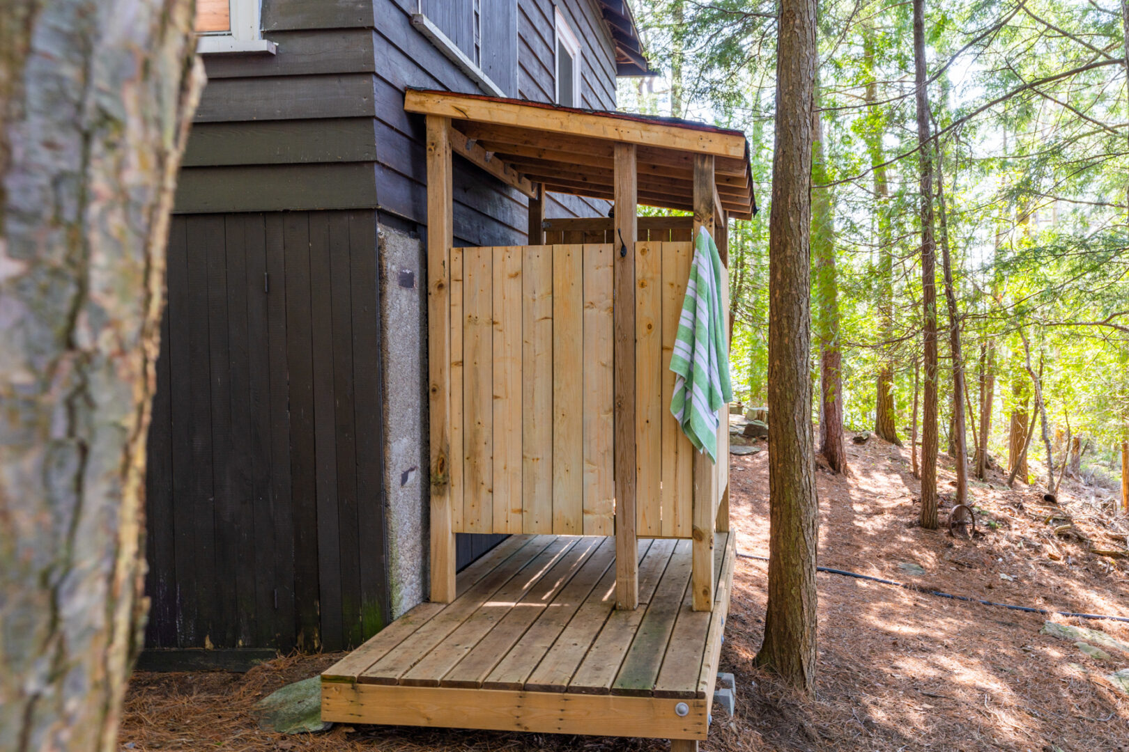 An outdoor shower extends off the side of a small cottage.