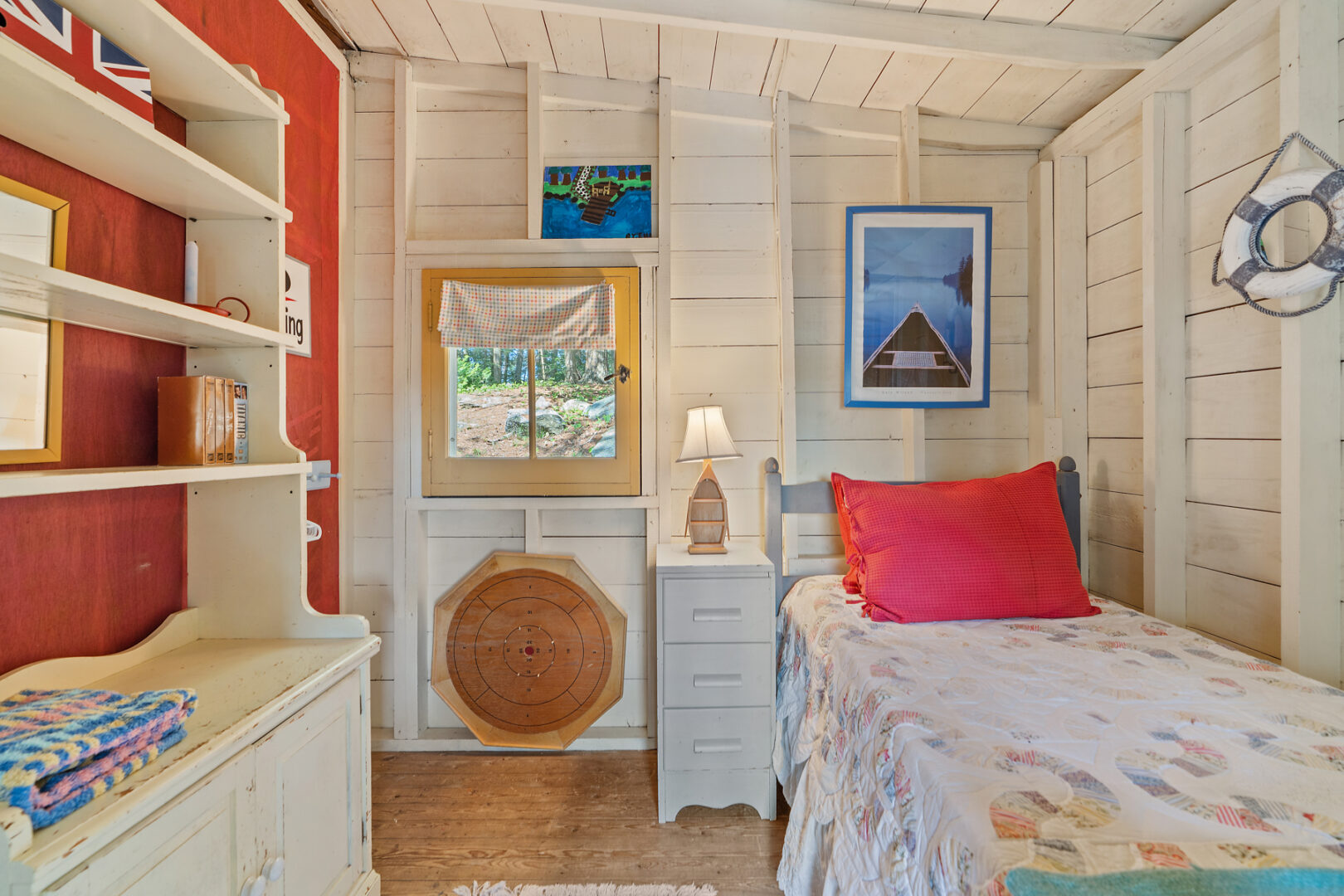 A small, bright bedroom with a single bed and white shelves.