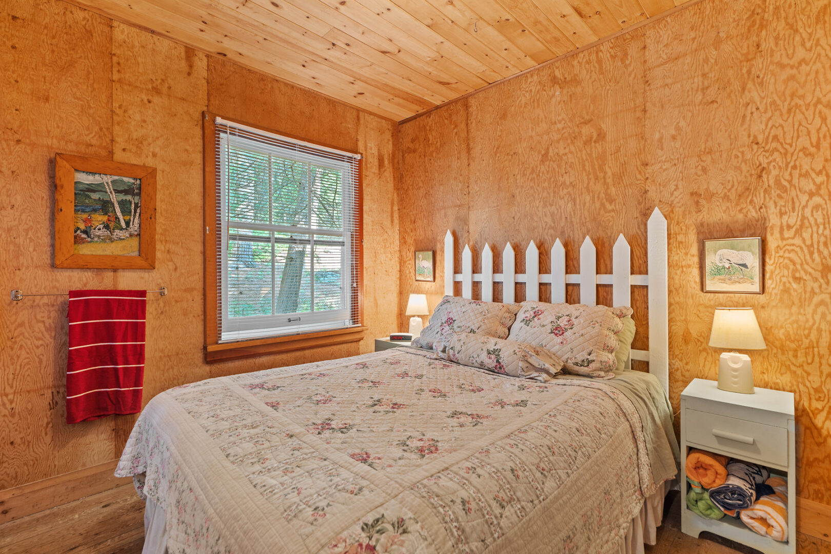 A bright bedroom with wood-panelled walls, a window, and a large bed.