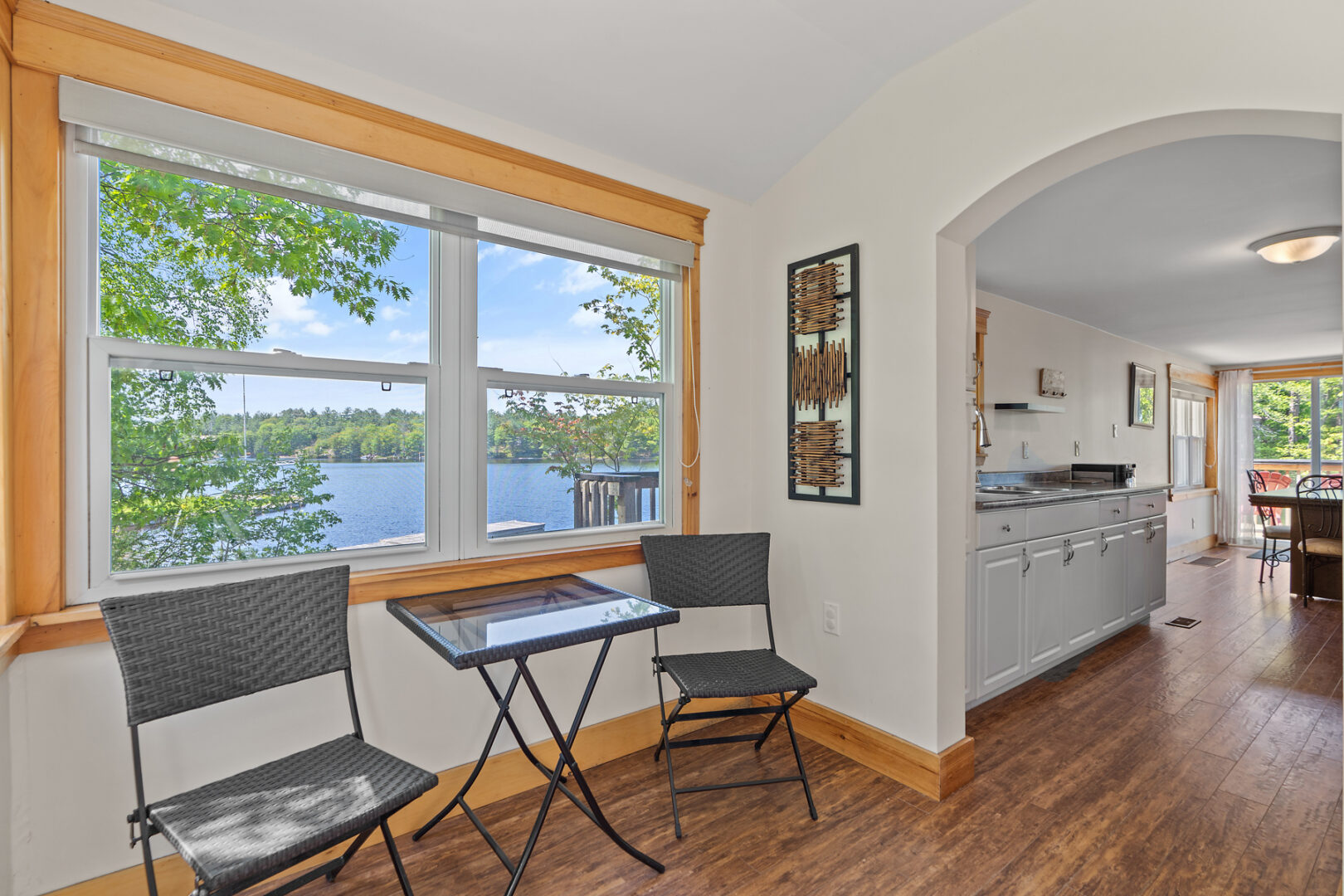 A small table and two chairs sits in front of a window in a small front entrance area of a cottage.