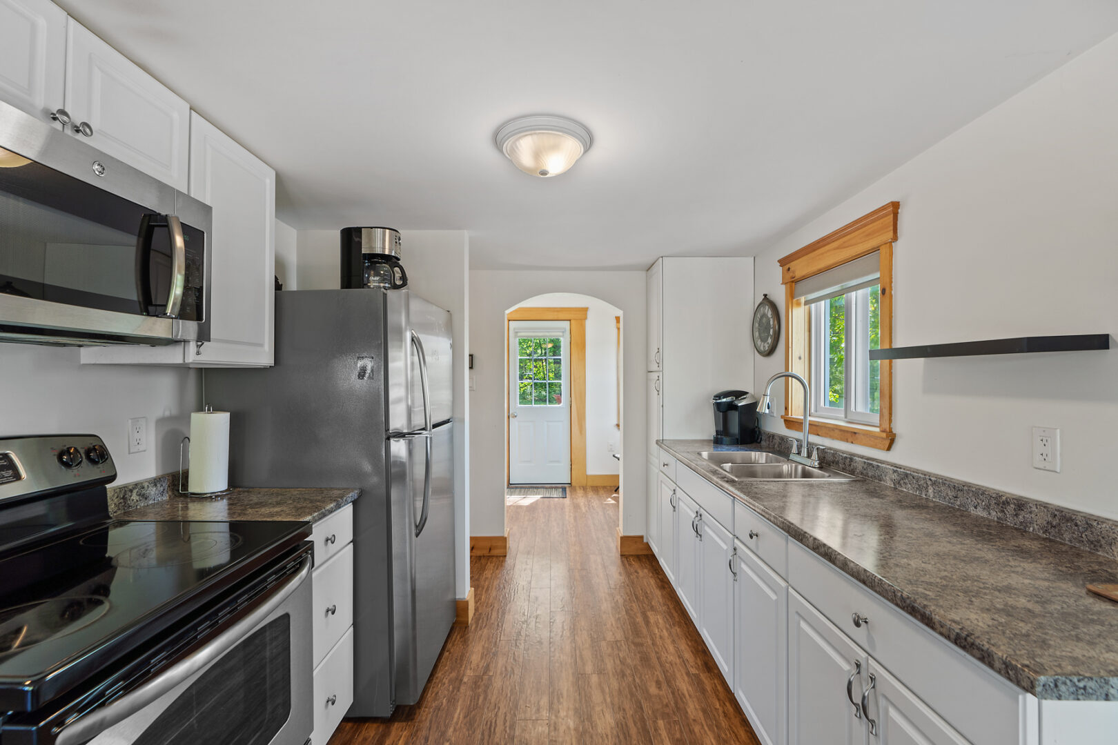 A narrow but bright stretch of kitchen with white cabinets, lots of counter space, and updated appliances.