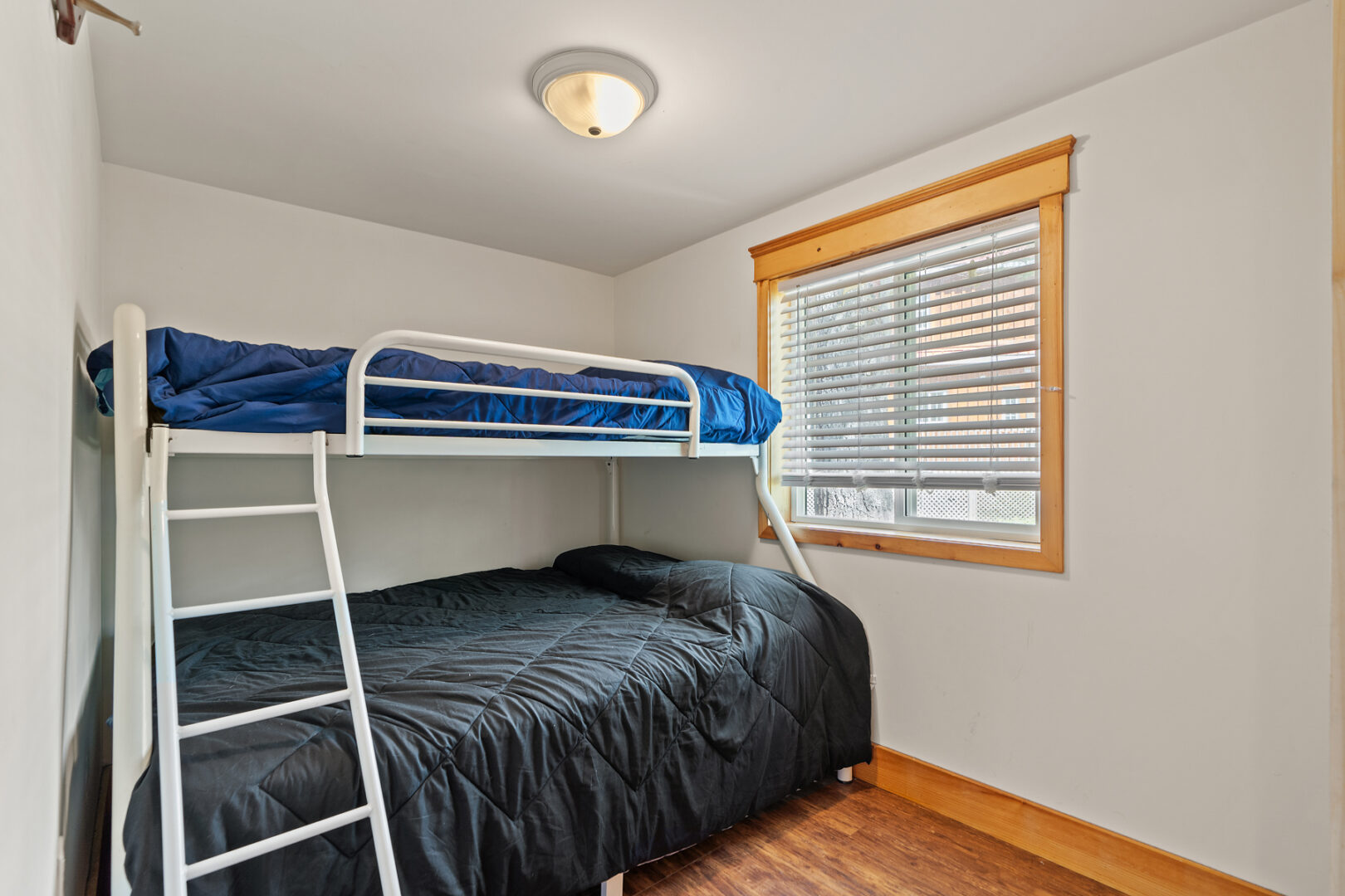 A small, bright bedroom with a set of bunkbeds and a big window.