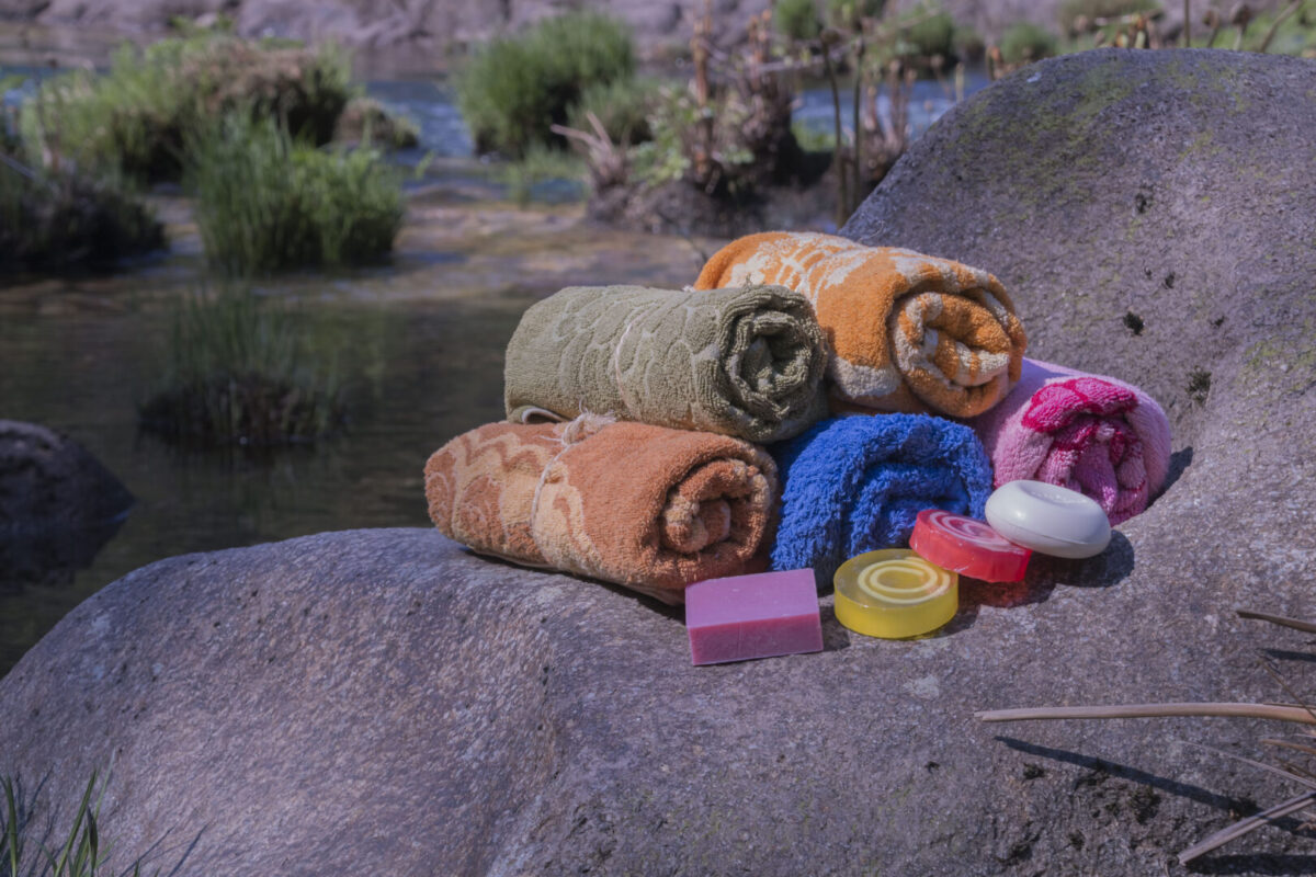 shower towels and soap on a rock by water