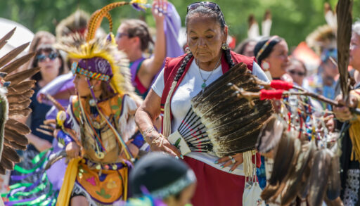 An elder surrounded by youthful and cheerful members of her indigenous community at the 2017 Ottawa Summer Solstice Indigenous Festival at Vincent Massey Park.
