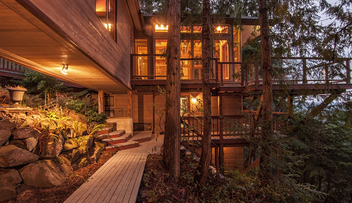exterior of large wooden cottage with lots of windows among the trees