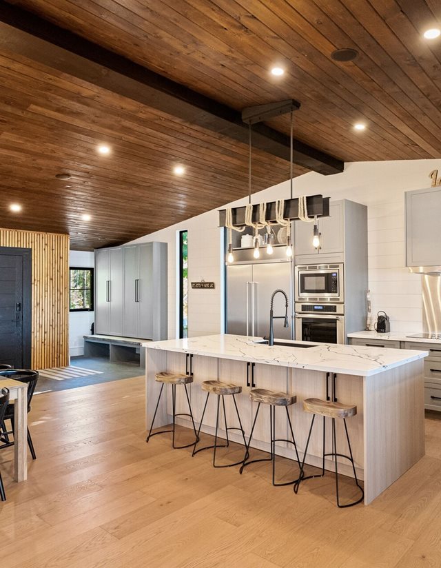 chef's kitchen with white island and wooden ceiling