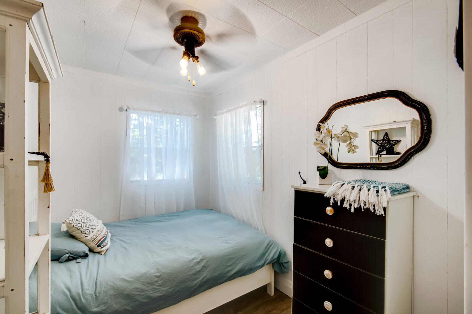 A small but bright bedroom with a single bed and a dresser.