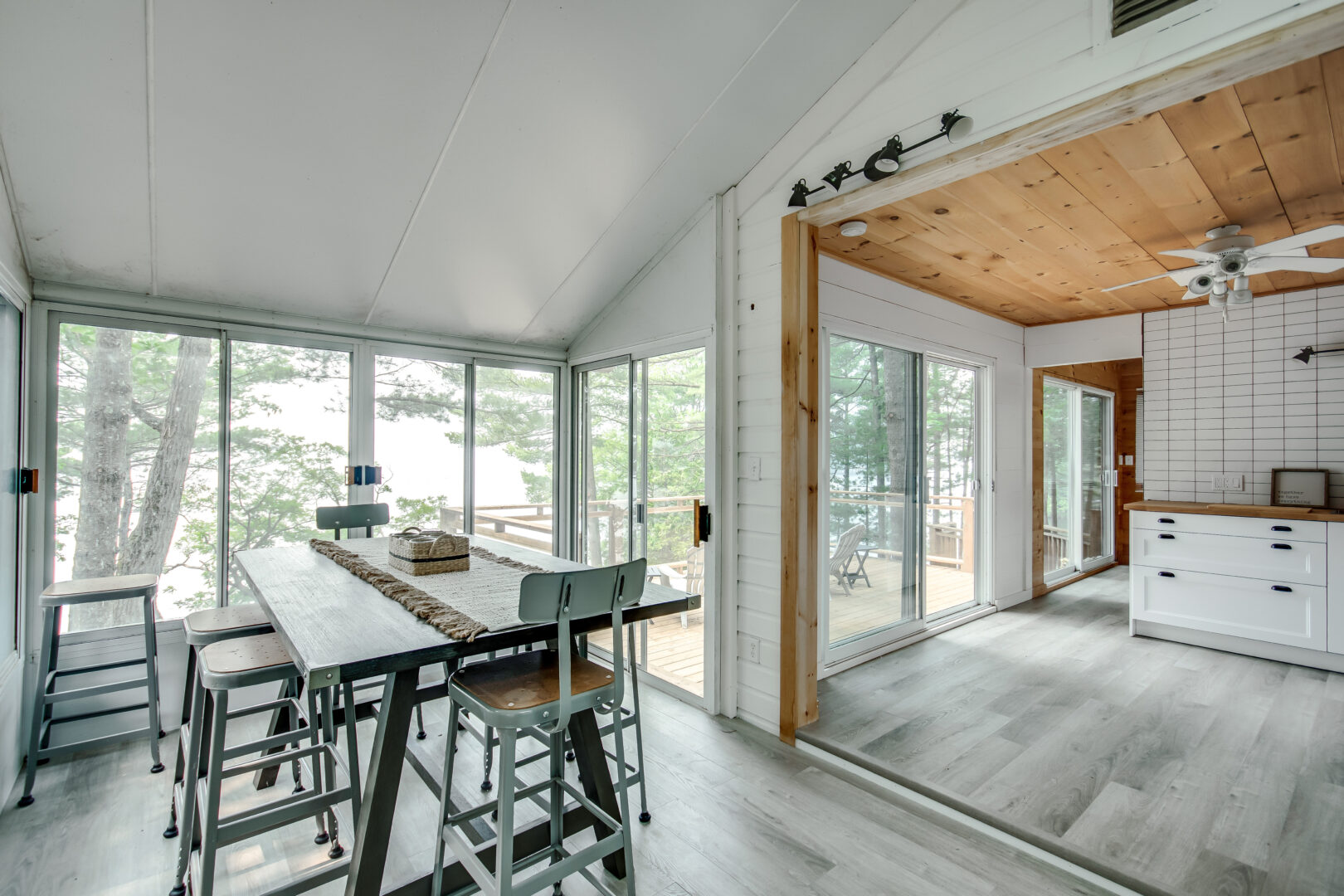 A dining area flows into a kitchen. Large, floor-to-ceiling windows line the whole exterior wall.
