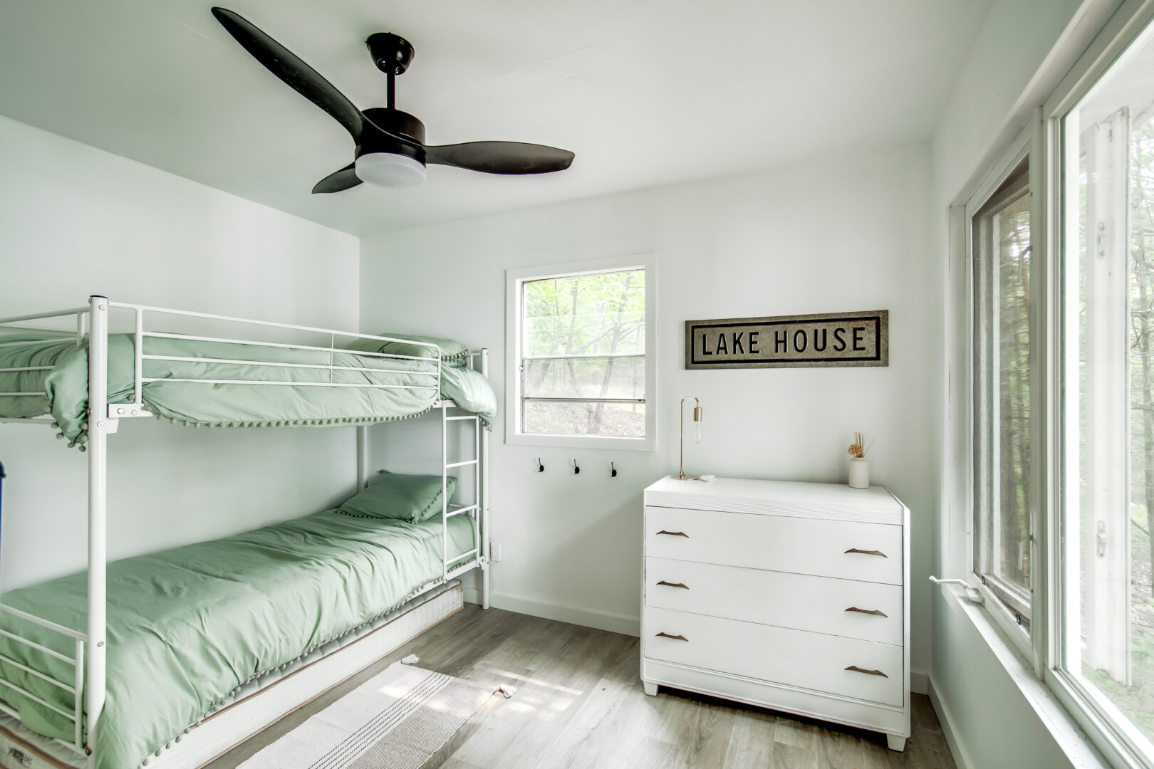 A bright bedroom with bunkbeds and a dresser.