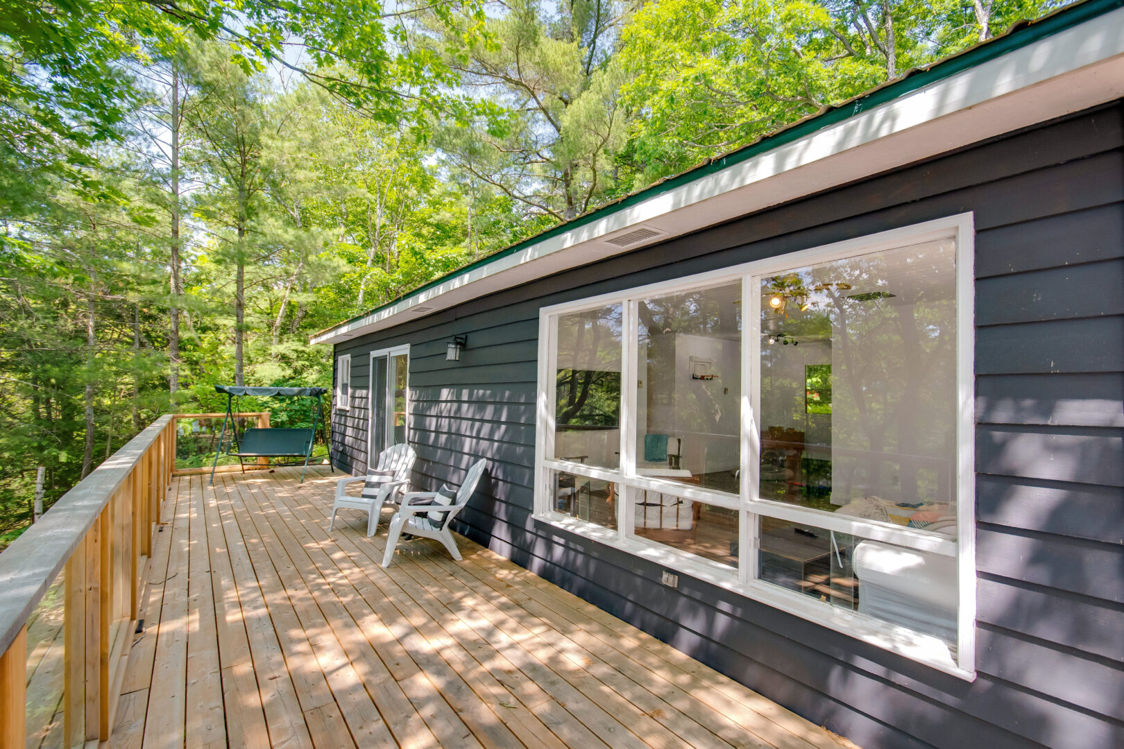 A long deck off the back of a cottage with large windows.