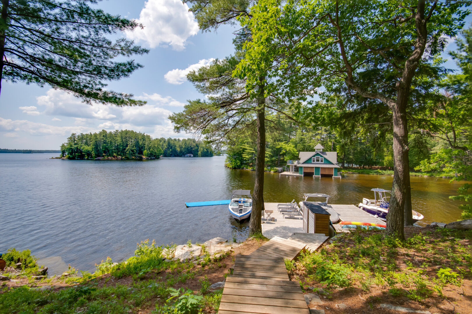 A dock extends into a blue lake off a tree-lined shore.