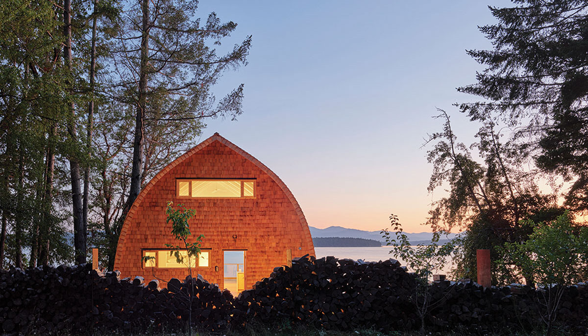 the exterior of the acorn gothic-arched cabin photographed at dusk with the lake in the background