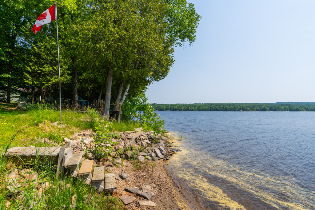Wooden steps lead down to the sandy shoreline of a lake.