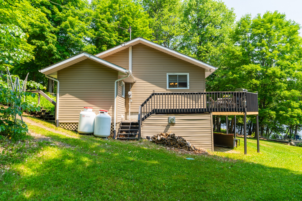 The side of a two-storey house on a grassy hill. A deck extends off the second floor.