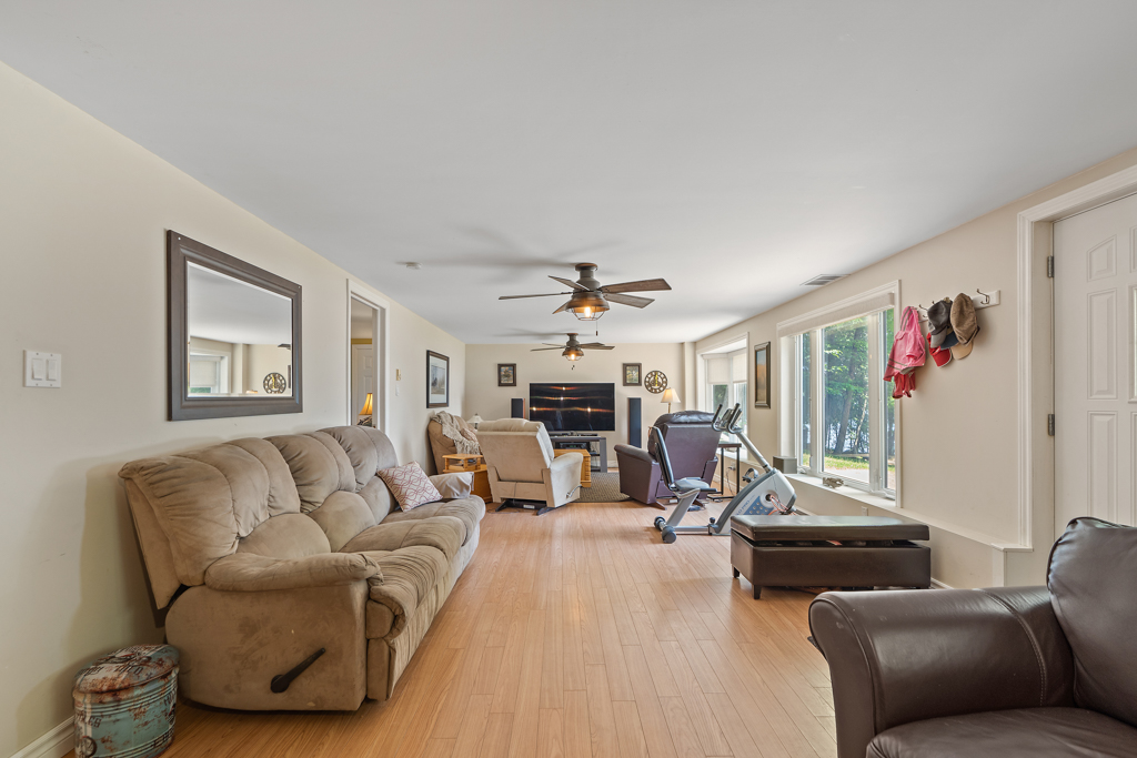 A long, narrow, bright lower-level living space with comfortable-looking furniture and a fireplace.