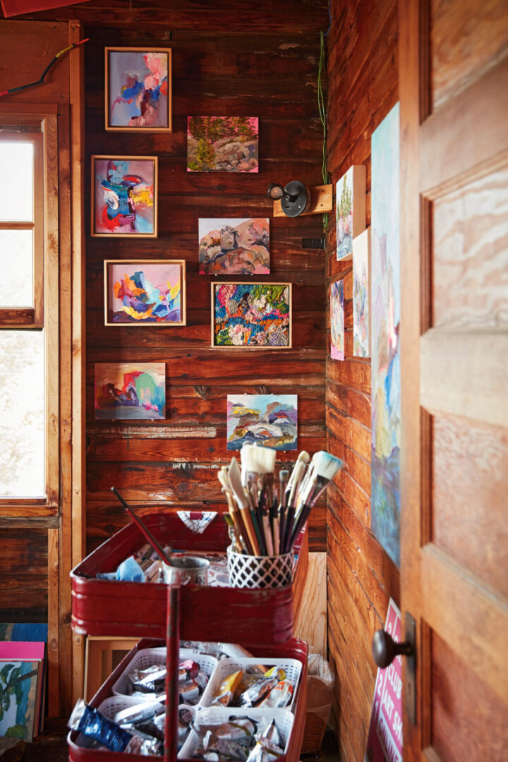 The inside of Kara's studio, with art on the walls and materials in a cart