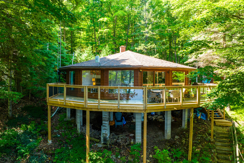 A cottage with a round exterior sits amongst trees.