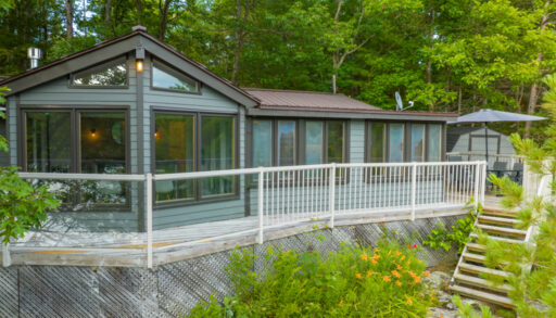 A large cottage with big windows and a long deck.