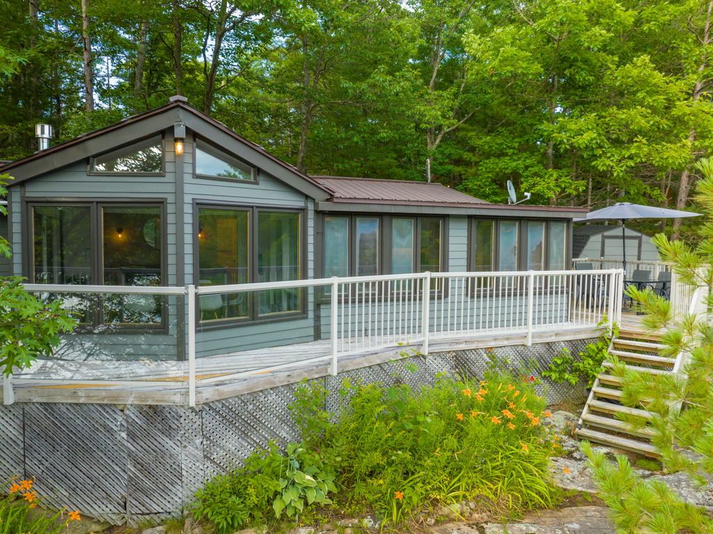 A large cottage with big windows and a long deck.