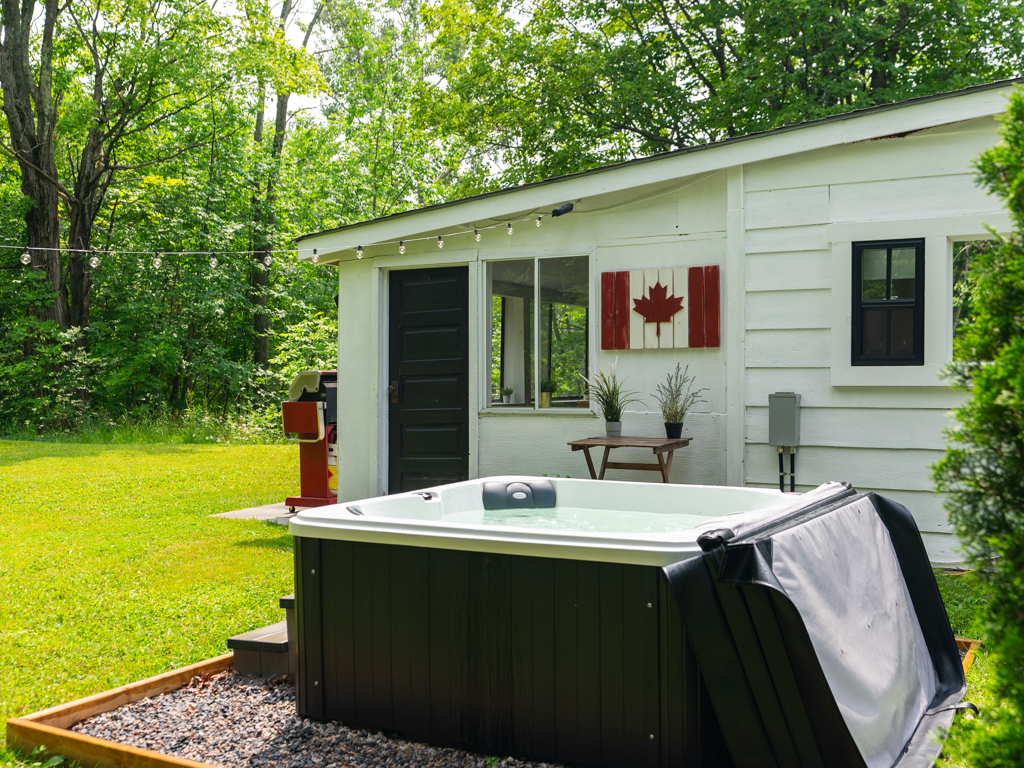 A hot tub sits beside a small house in a rural area.