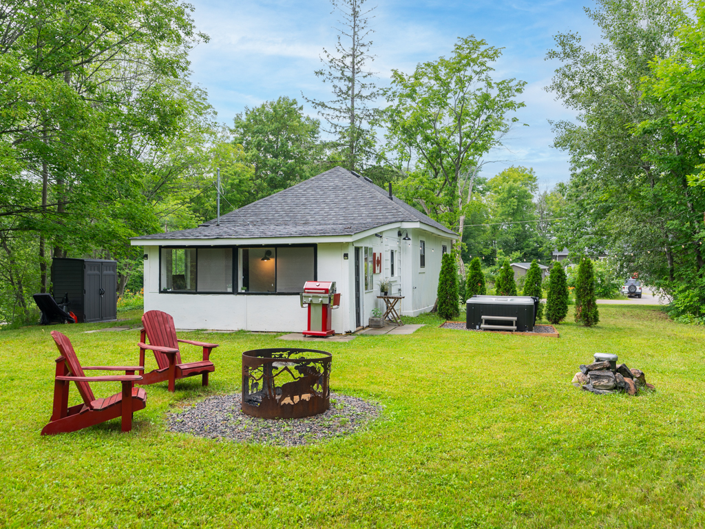 Backyard of a small rural house, with a fire pit and a hot tub.