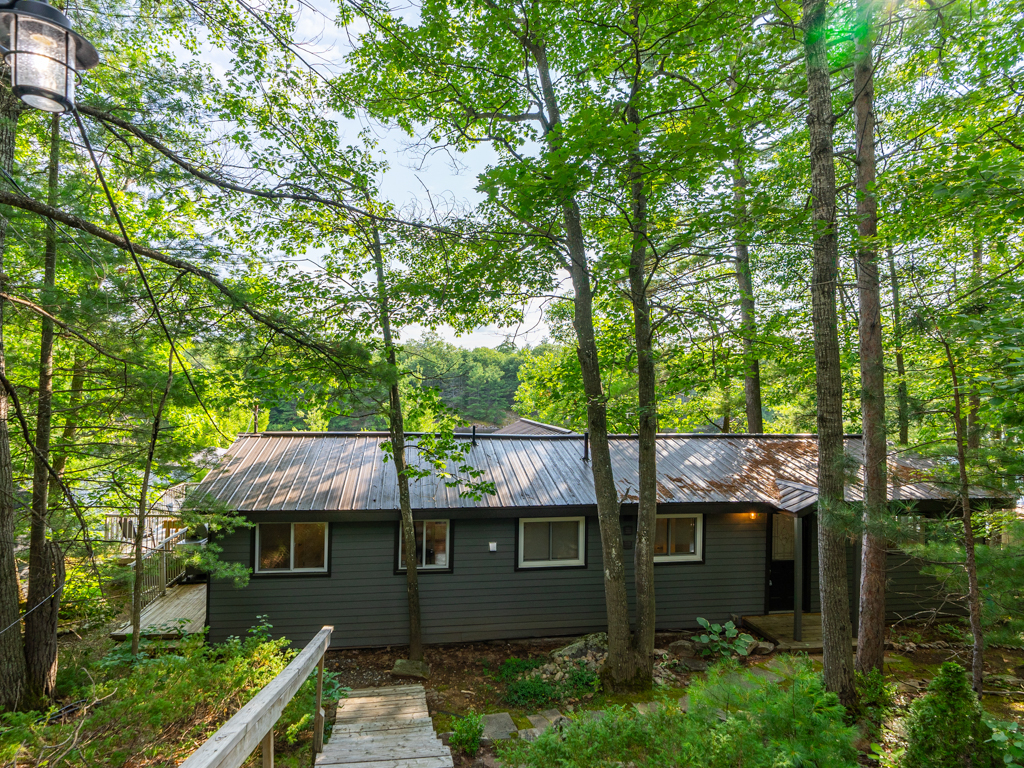 Wooden stairs lead down to the front entrance of a long cottage.