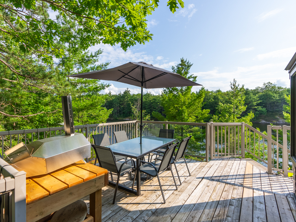 A big deck area with an umbrella and a table, looking out over the lake.