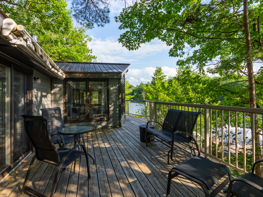 A wide deck off a cottage with lots of seating.