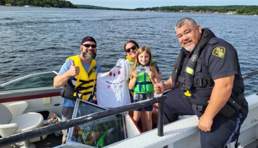 OPP officer posing with family receiving "I got caught wearing my lifejacket" shirt
