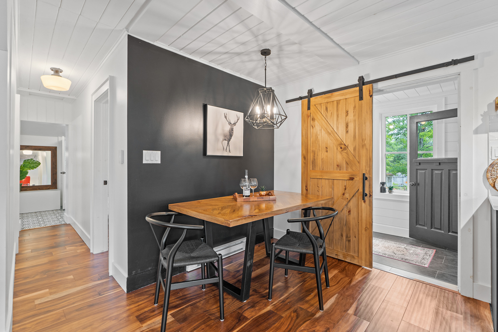 A small dining area with a table and chairs in front of a black accent wall.