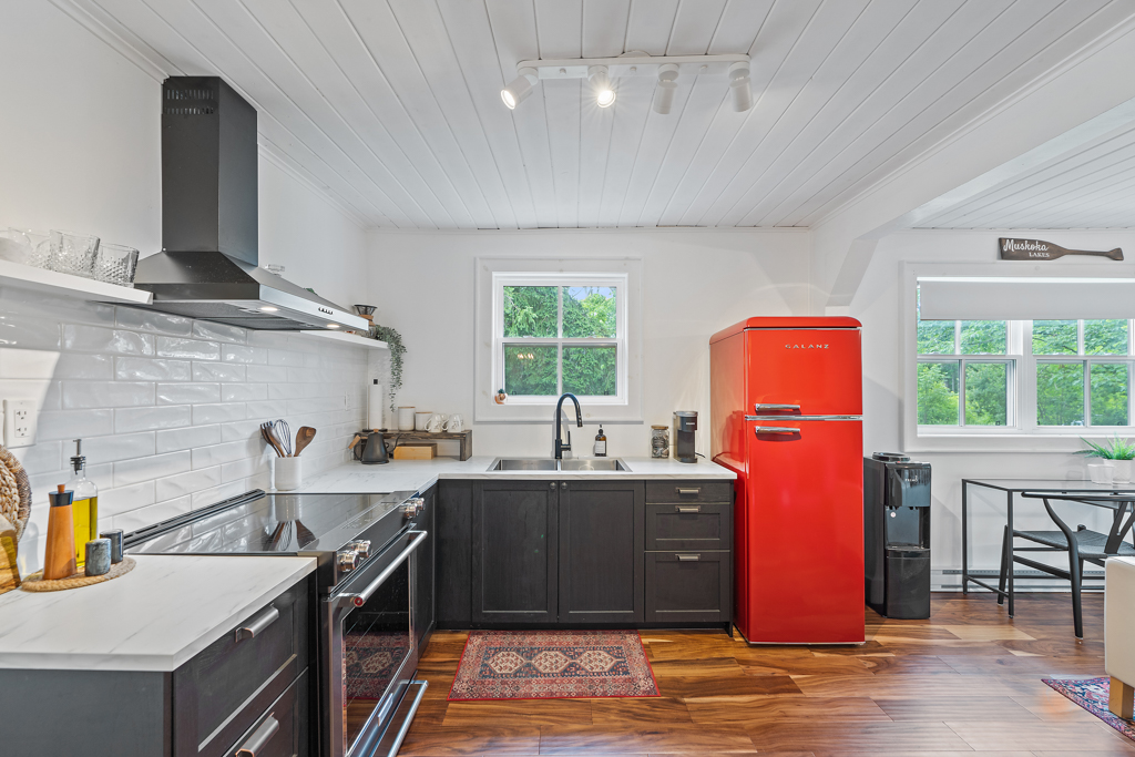 A modern kitchen with black cabinets and a red fridge.