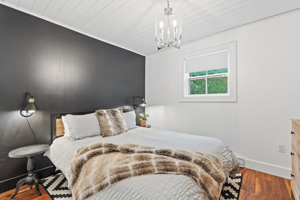A bright bedroom with a big bed in front of a black accent wall.