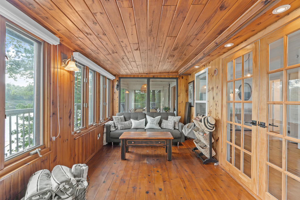 A big, wood-panelled sunroom with lots of windows and furniture for sitting.