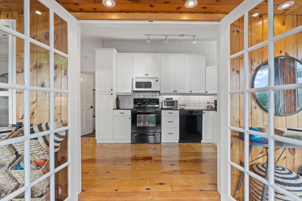 a double-door entrance leads from a sunroom into a kitchen.