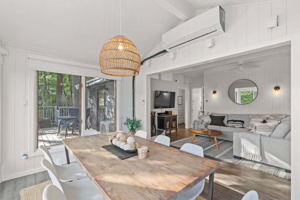 A bright dining area with a table and lots of windows that flows into a living space.