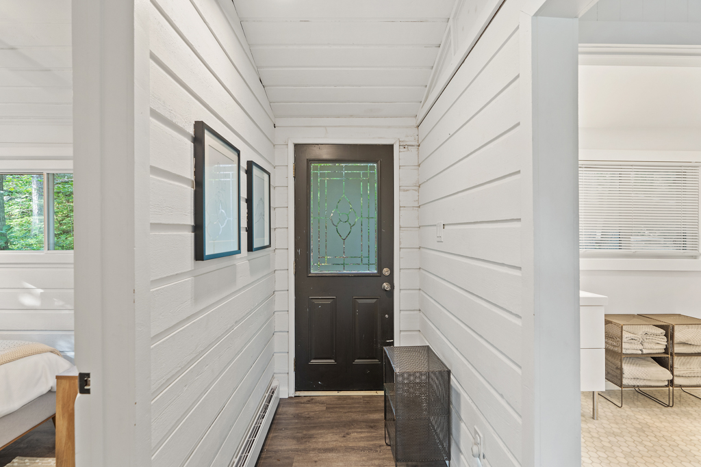 Inside the front entrance of a cottage, with a narrow hallway and white walls.