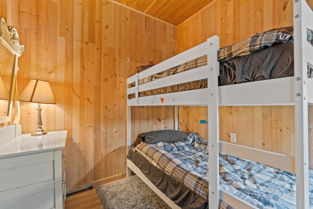 A small bedroom with wood-panelled walls and bunkbeds.
