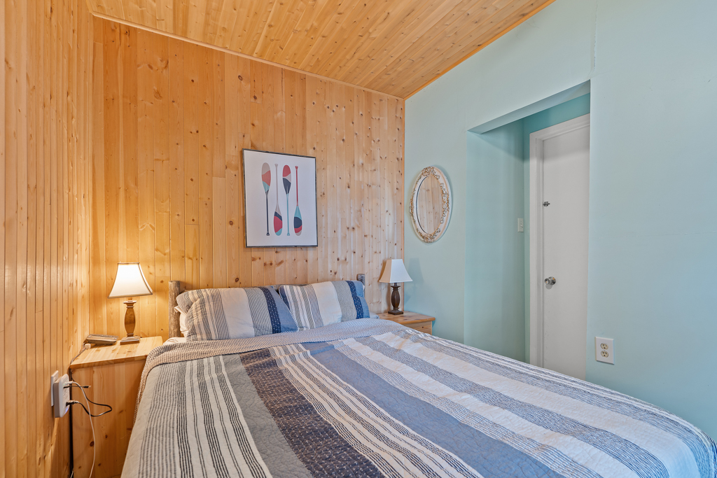 A small bedroom with wood-panelled walls and a big bed.