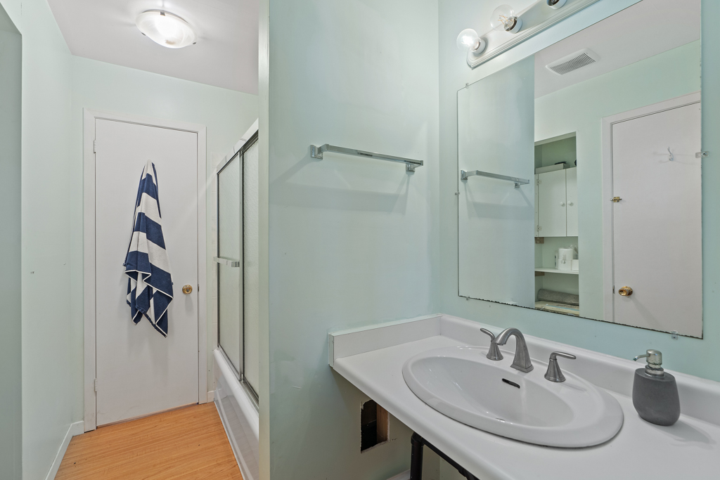 A bathroom with a sink and a shower-tub combo.