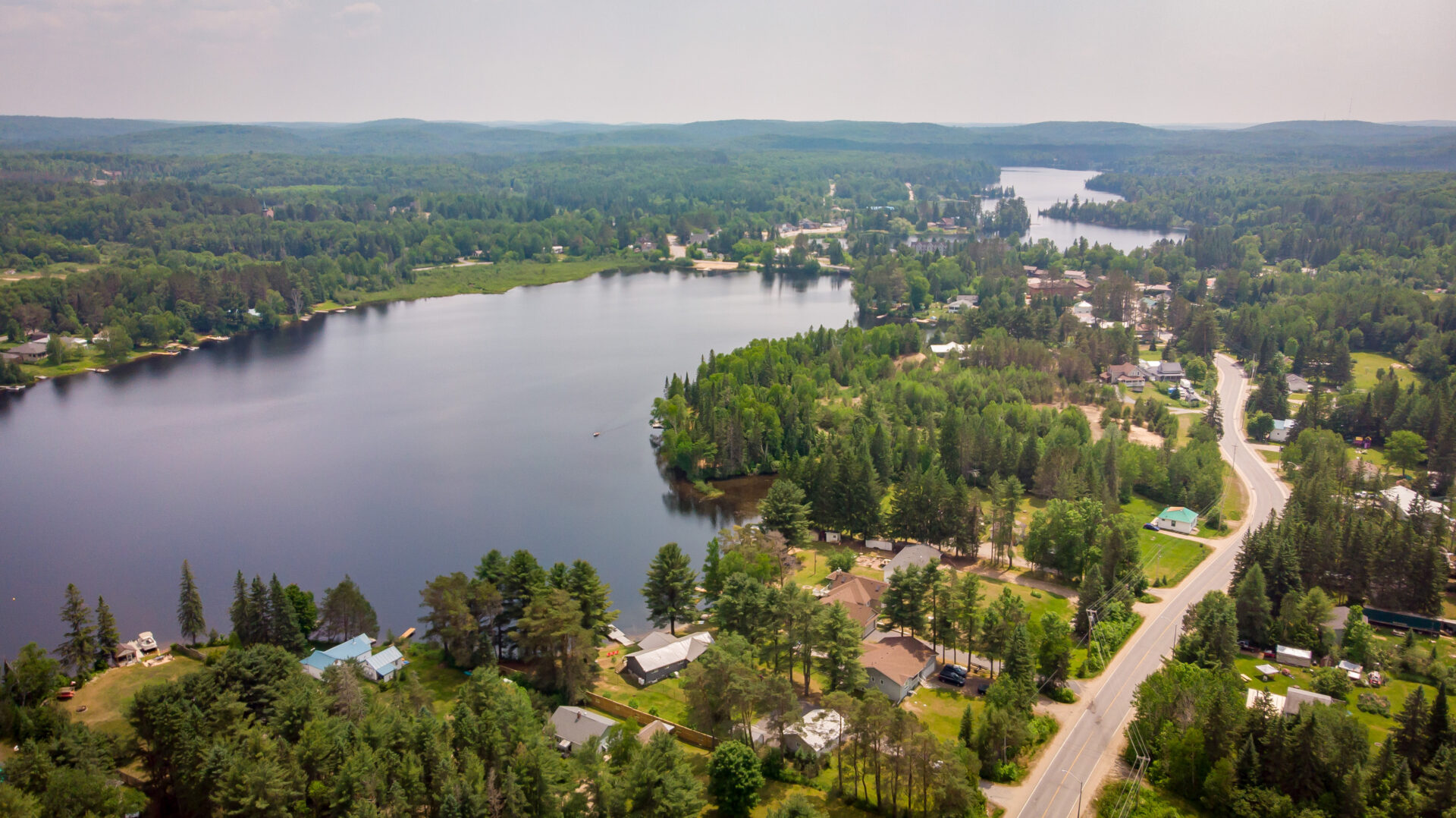 An overhead view of a small, populated lake, with many properties lining the shore.